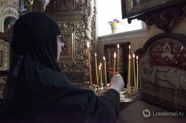 Сестра зажигает свечку в Храме Казанской иконы Божией Матери.